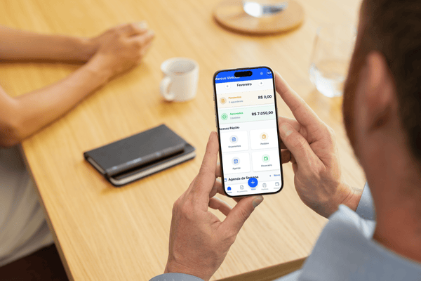 App Orçamento Fácil sendo usado no celular sobre mesa de trabalho